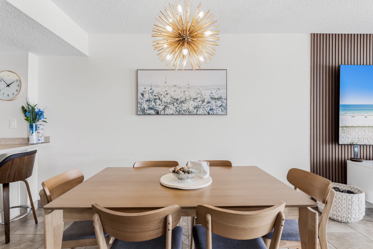 Gather around the warm wood dining table beneath a stunning starburst chandelier. The bright, open space invites you to share meals and make memories with loved ones.