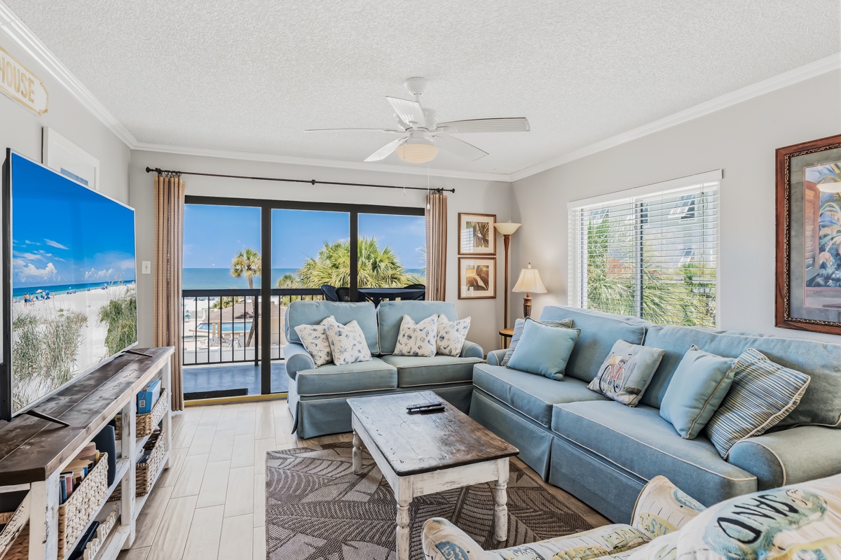 Relax in your coastal living room with sweeping ocean views framed by palm trees. Soft blue sofas invite you to unwind while gentle breezes flow through your balcony doors.