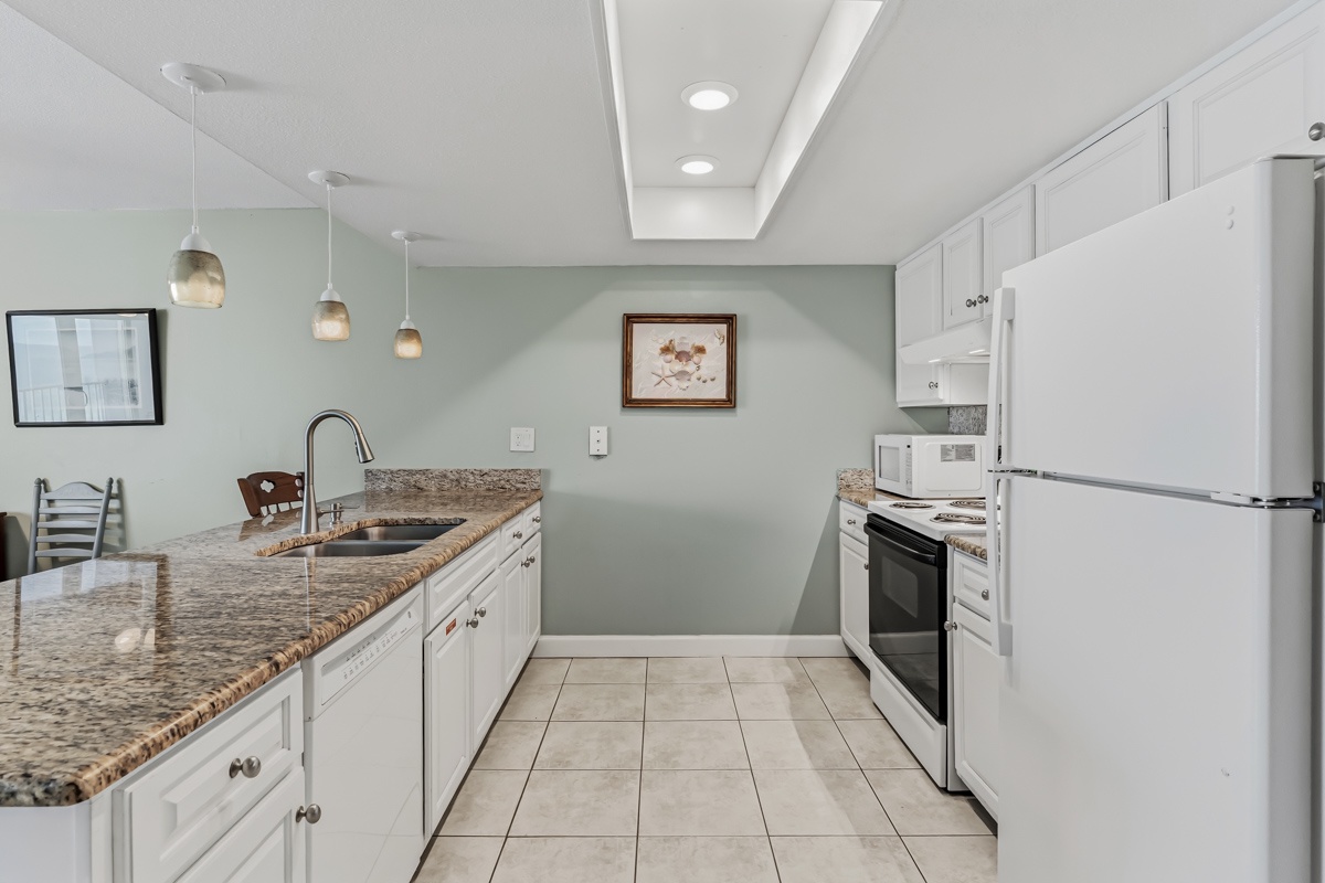 Your fully equipped kitchen features granite countertops, white cabinetry, and modern appliances—perfect for preparing meals together during your stay.