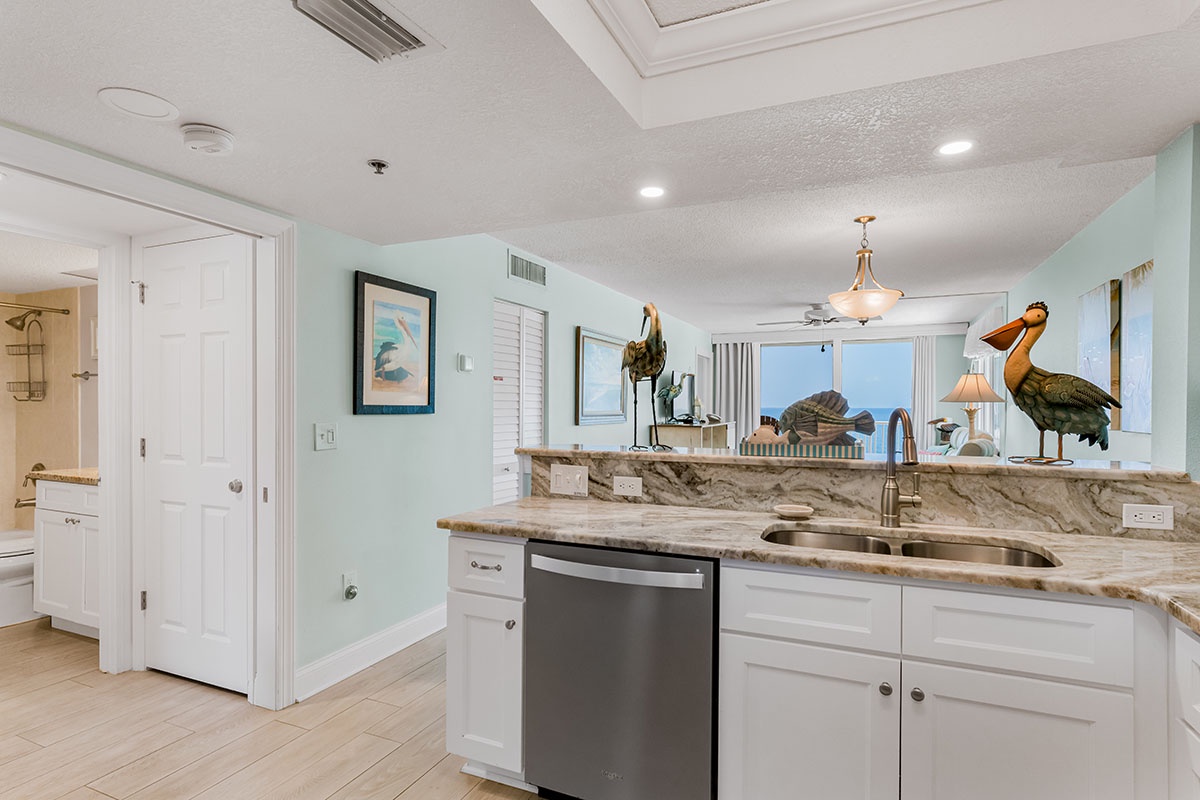 Your spacious kitchen features marble countertops, stainless steel appliances, and serene coastal views through the window.