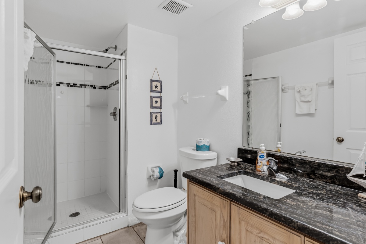 Freshen up in your bright, well-appointed bathroom with a spacious walk-in shower, granite vanity, and soft white towels waiting for you.