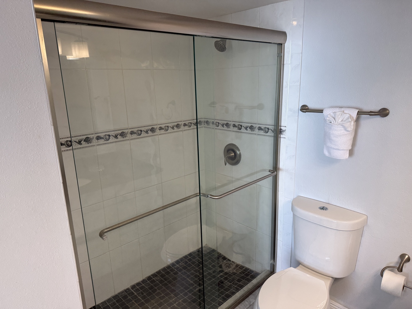 Step into your private spa-like bathroom featuring an elegant glass-enclosed shower with gorgeous decorative tile work and fluffy towels waiting for you.