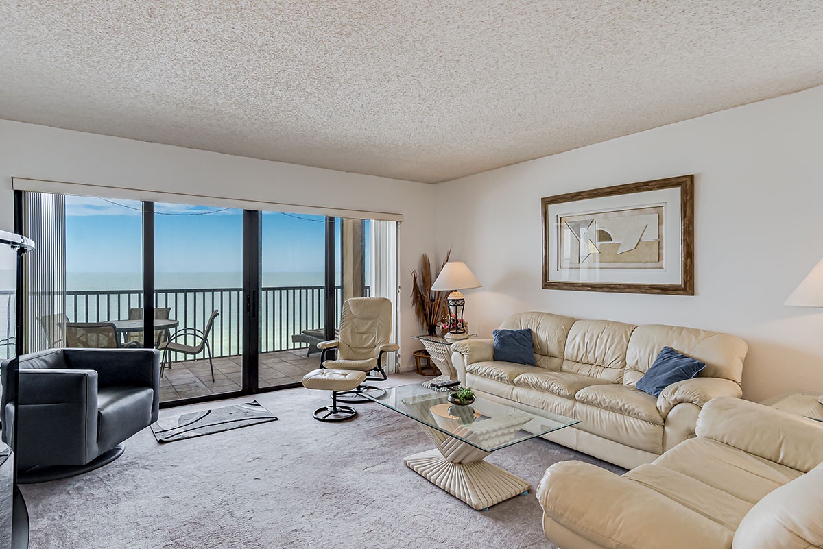 Relax in your spacious oceanfront living room with floor-to-ceiling windows showcasing endless beach views from your private balcony.