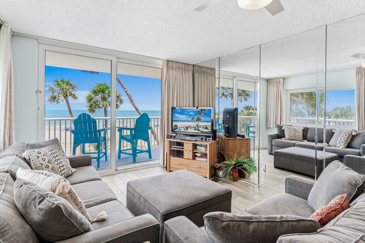 Sink into plush seating and take in stunning ocean and palm tree views through your private balcony doors—your perfect coastal retreat awaits.