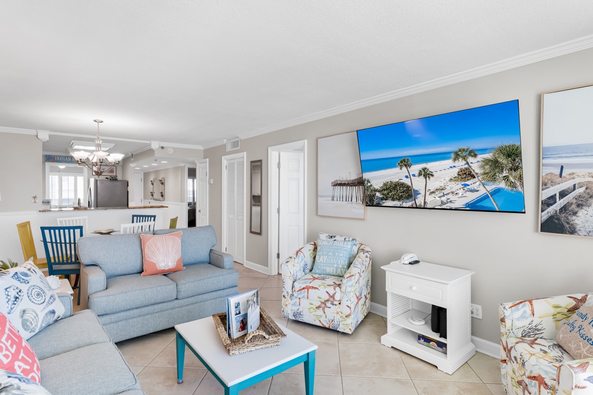 Relax in your bright, coastal-themed living space with ocean views adorning the walls and comfortable seating perfect for unwinding after beach days.