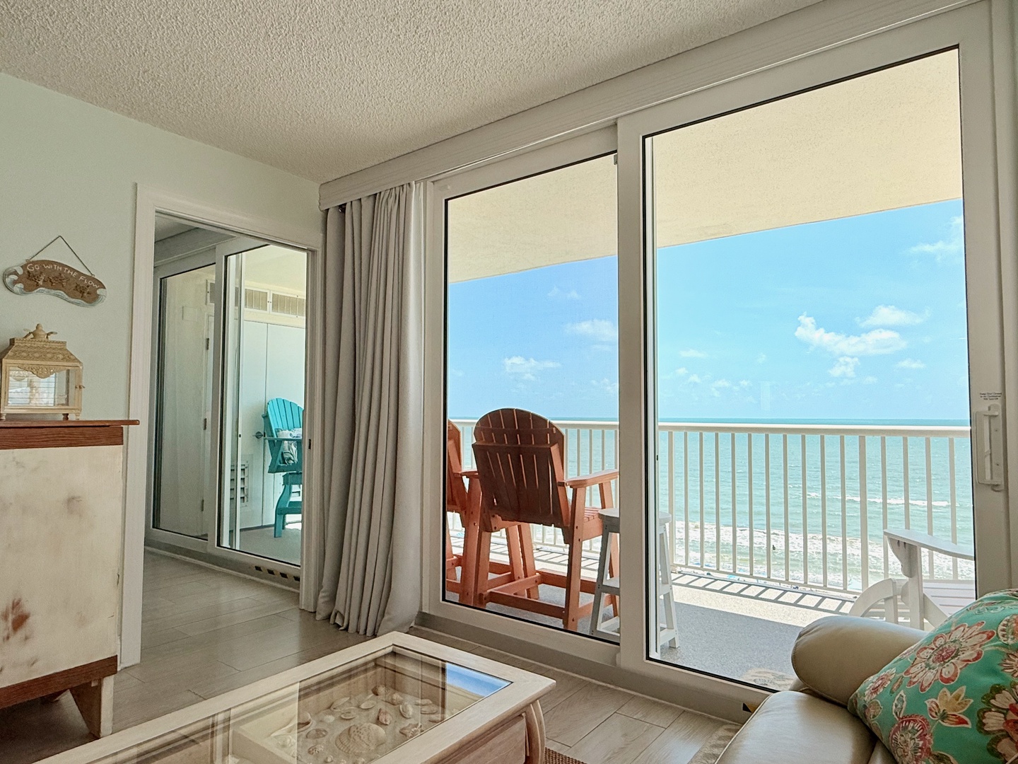 Step inside to discover your private balcony just steps away, where turquoise waters and white sands create your own oceanfront sanctuary. The coastal decor and glass doors frame your view, inviting you to unwind in paradise.