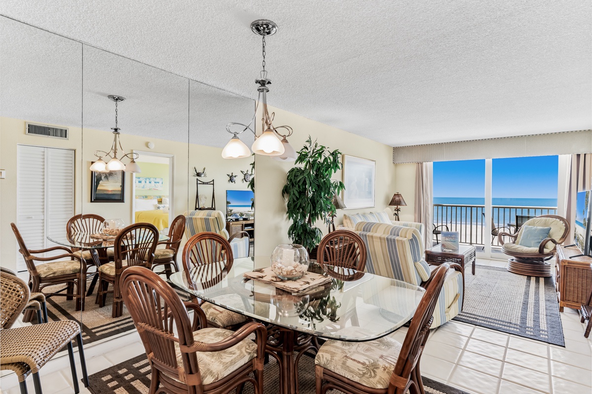 Relax in your open living and dining space where coastal style meets comfort. Gather around the elegant glass dining table, unwind on the striped sofa, and let your gaze drift to the stunning ocean view through the balcony doors.