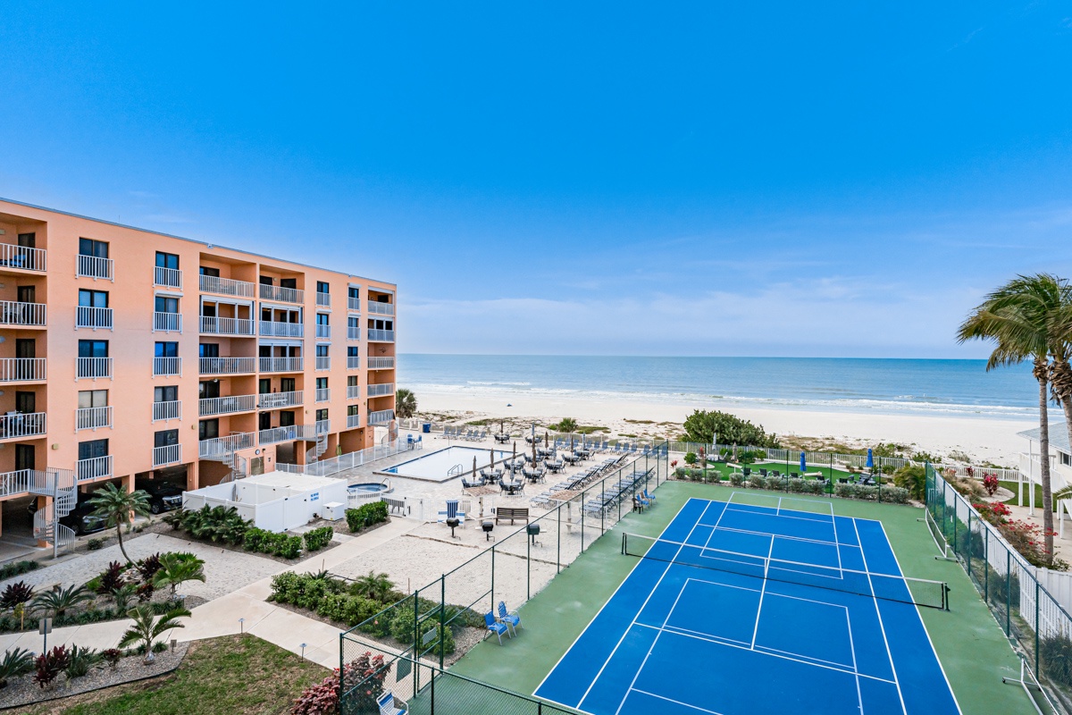 Beachfront property featuring tennis courts, pool area, and direct access to pristine white sand beach with crystal-clear waters.