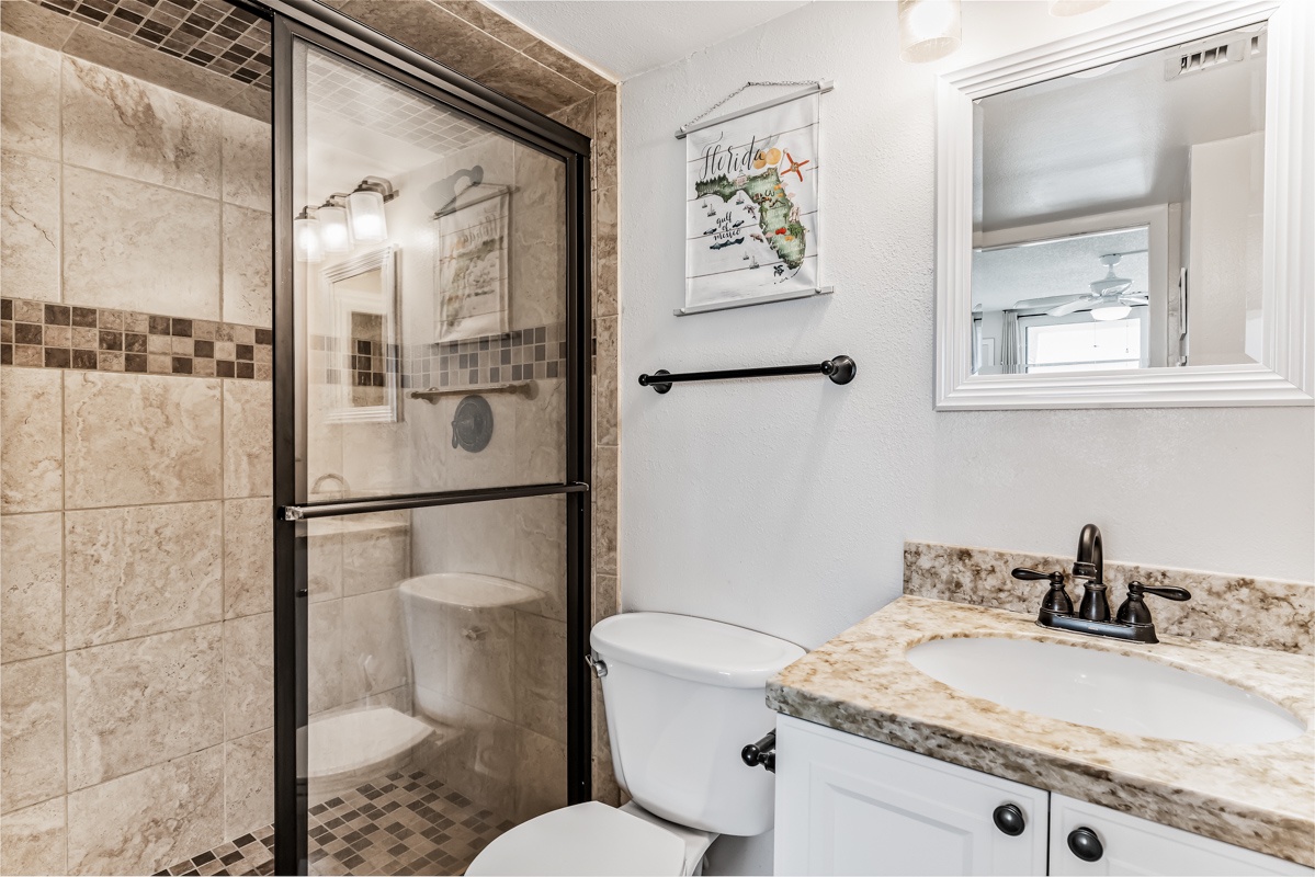 Step into your stylishly updated bathroom, featuring a spacious walk-in shower with elegant tiling, granite countertops, and thoughtful Florida-themed touches to make you feel right at home.