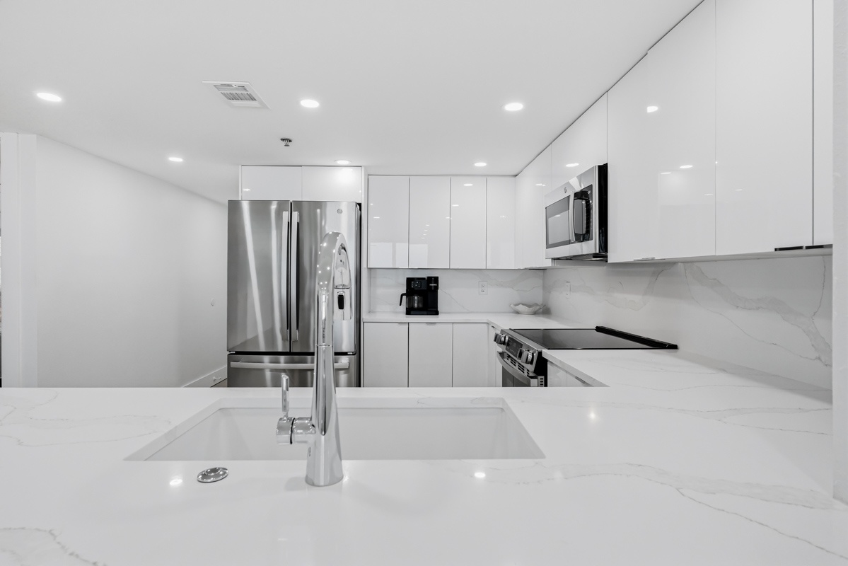 Your sleek modern kitchen features pristine white countertops, stainless steel appliances, and everything you need to create memorable meals.
