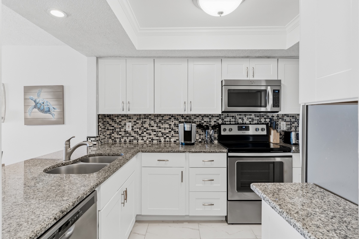 Step into your fully equipped kitchen featuring granite countertops, stainless steel appliances, and stylish mosaic backsplash—perfect for preparing meals during your stay.