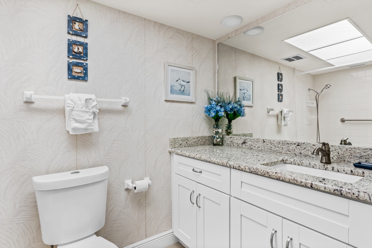 Your stylish bathroom features granite countertops, elegant coastal decor, and fresh flowers that create a spa-like retreat for your daily routine.