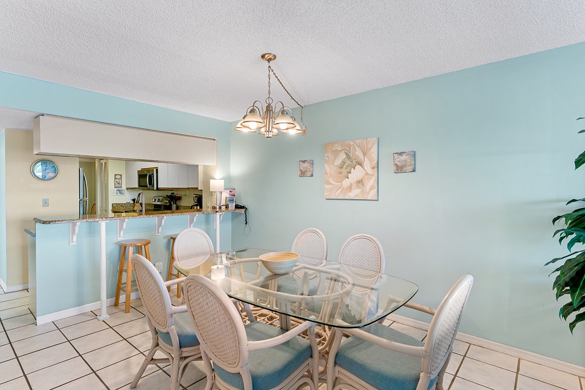 Gather around your elegant glass dining table for memorable meals in this bright, airy space with soothing mint walls and coastal charm.