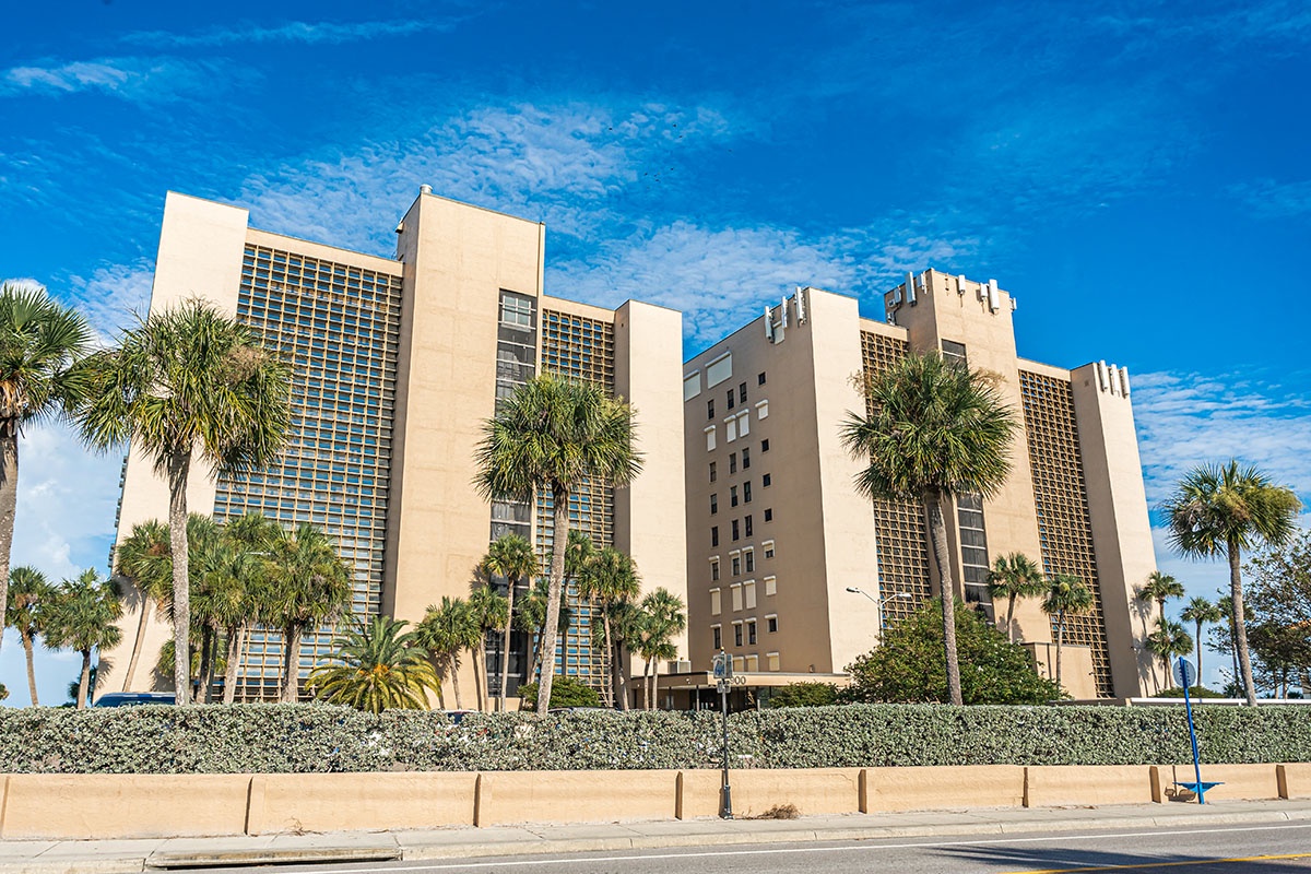 Multi-tower beachfront complex with tropical palm landscaping against brilliant blue skies.