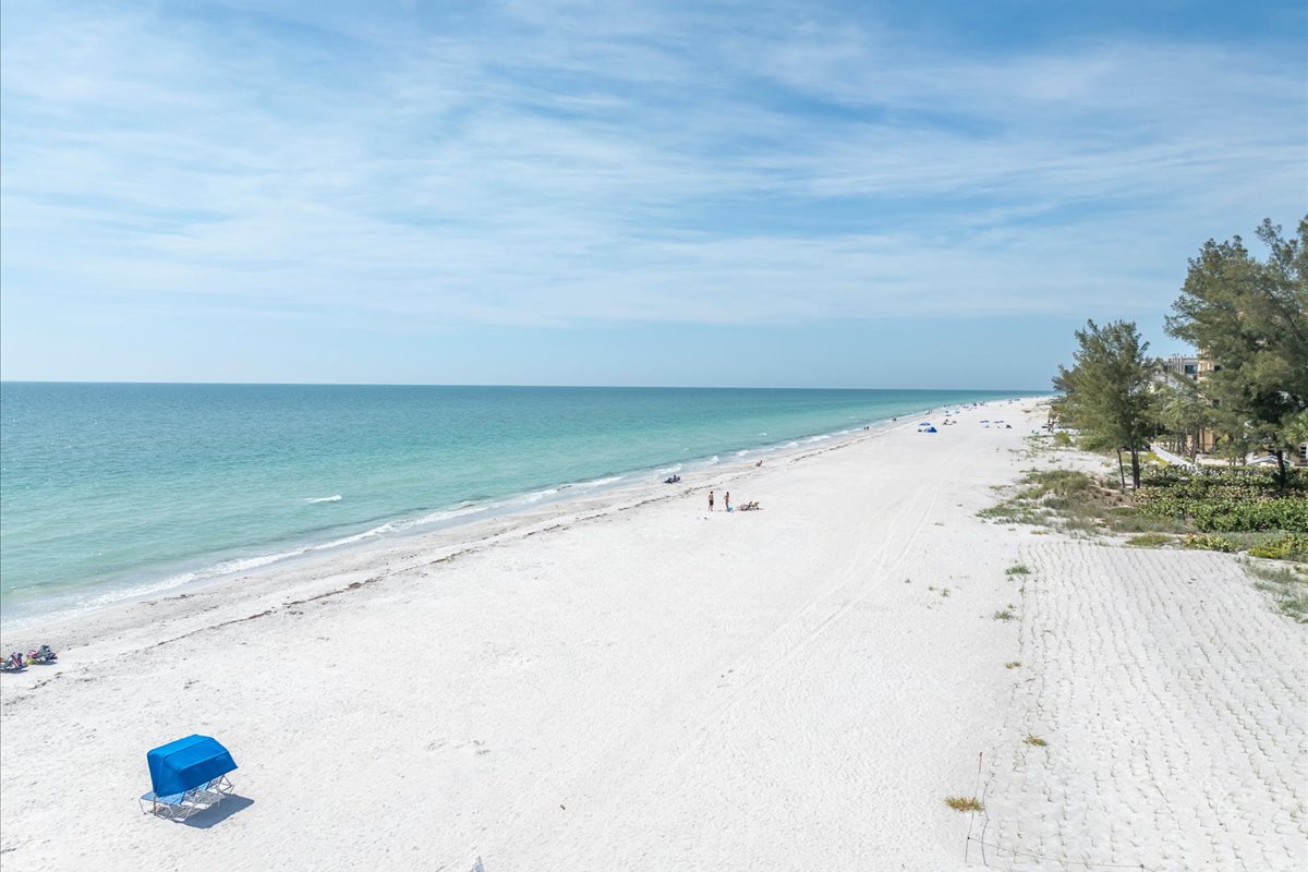 This pristine white-sand beach stretches along turquoise waters, offering a peaceful coastal setting near the property with gentle waves and natural vegetation.