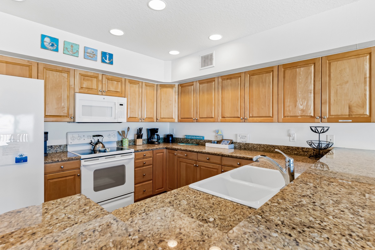 Prepare your favorite meals in this fully equipped kitchen featuring granite countertops and warm wood cabinetry.