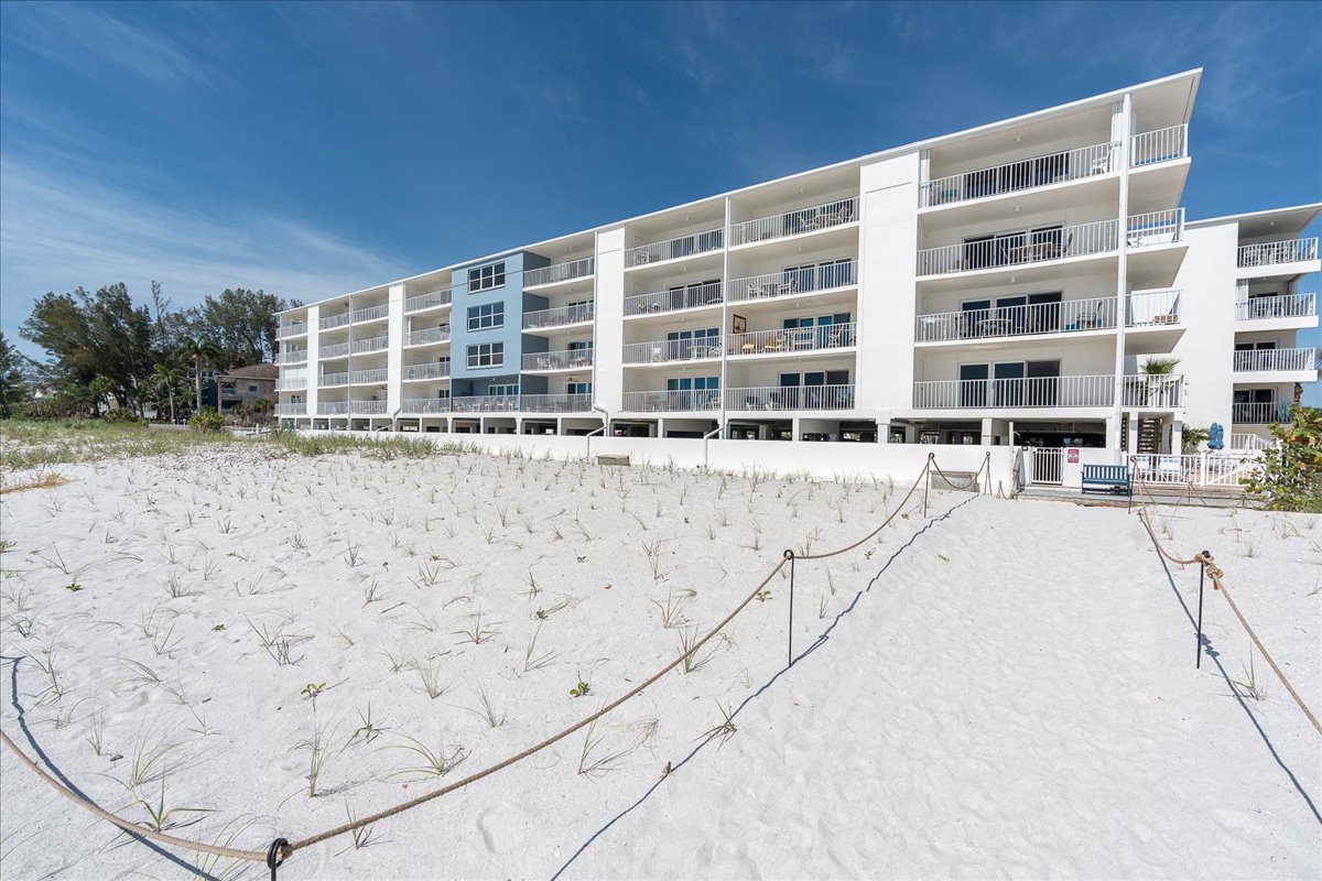 A beachfront property offering direct access to white sand and gentle dunes, with modern architecture and private balconies overlooking the shore.