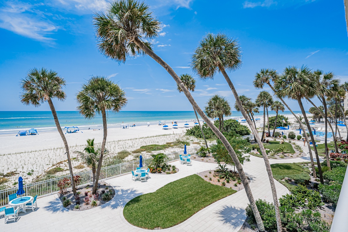 White-sand beaches meet turquoise waters beneath swaying palms, where landscaped grounds and lounge chairs create a serene coastal setting ideal for sun-soaked relaxation.