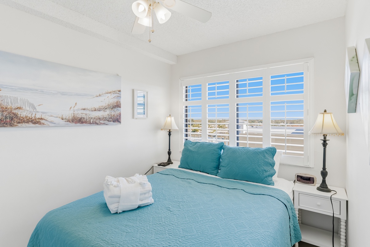 Wake up in your serene bedroom with soft ocean-inspired linens and plantation shutters filtering gentle morning light across crisp white walls.