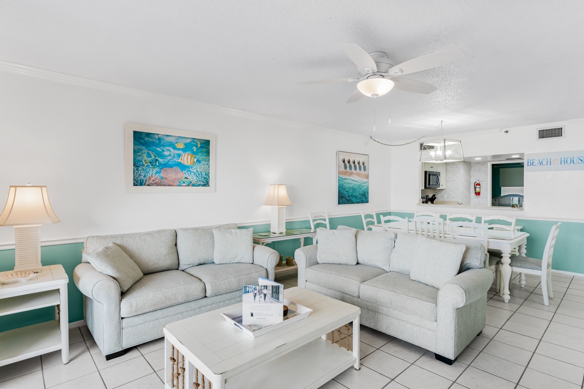 Relax in your bright coastal living room with comfortable seating, ocean-themed artwork, and an open layout that flows into your dining area.