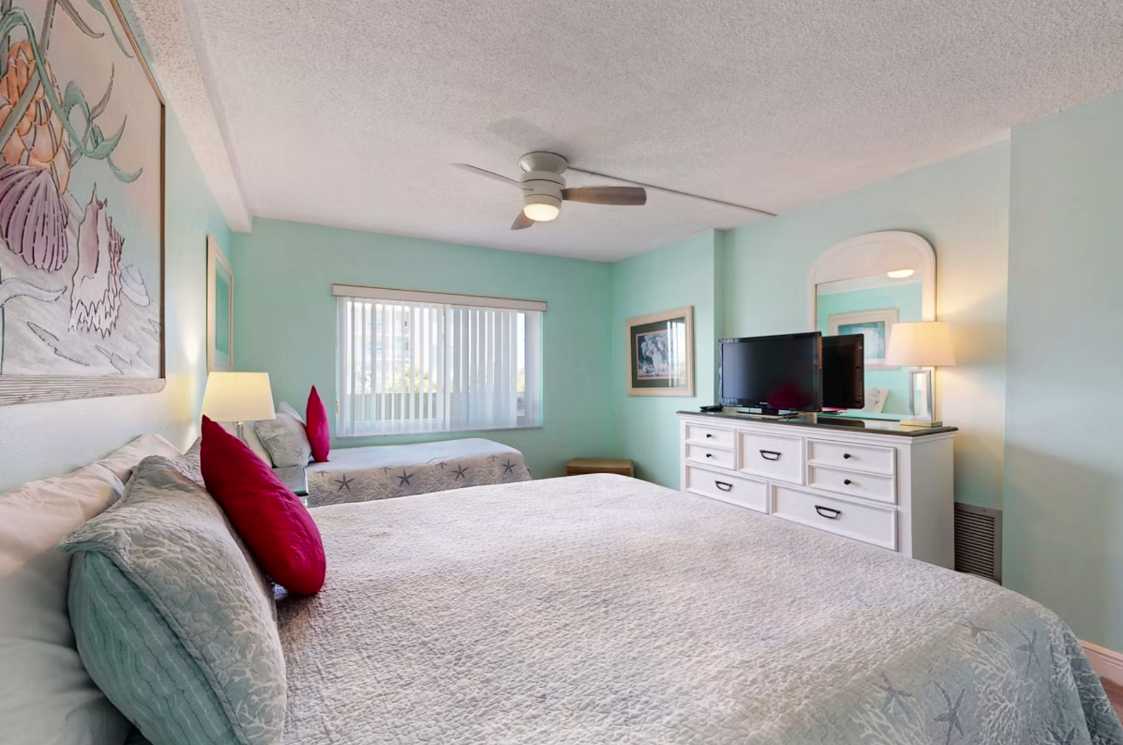 Relax in your bright, coastal-inspired bedroom with soft turquoise walls, 2 comfortable beds, a King and a Twin, and a gentle ceiling fan. Unwind after beach days with your favorite shows on the flat-screen TV.