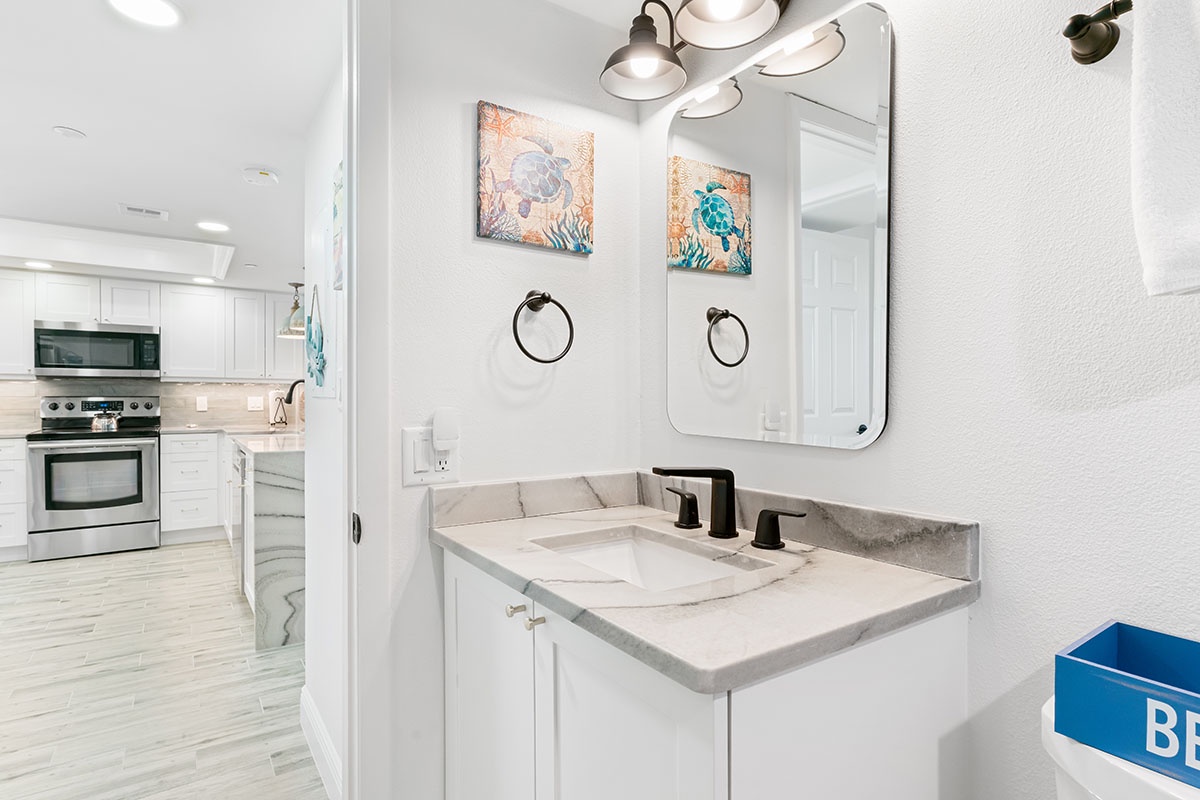Freshen up in your stylish bathroom featuring marble countertops, modern fixtures, and coastal artwork that sets a serene tone for your stay.