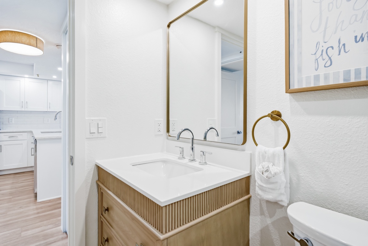 Refresh in your bright bathroom with elegant gold fixtures and modern vanity that connects to your fully-equipped kitchen.