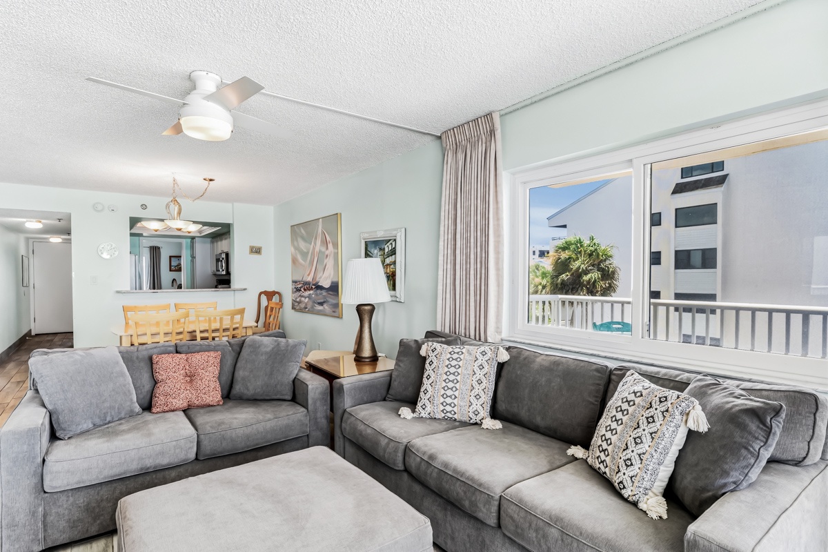 Settle into plush gray sofas and feel right at home in this bright, breezy living area. Your private balcony reveals swaying palms and coastal charm just beyond the sliding doors.