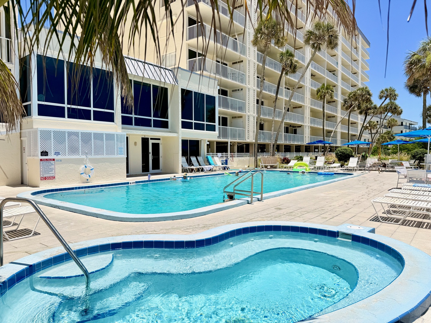 Dive into your sunny escape at this inviting pool area surrounded by swaying palms. Lounge poolside or soak in the bubbling spa—your perfect beachside retreat awaits.