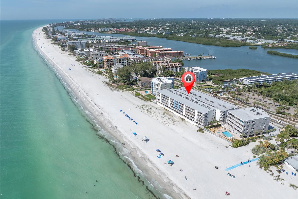 Aerial view of a beachfront property situated on pristine white sand between the turquoise Gulf waters and a tranquil bay, offering direct beach access in a serene coastal setting.