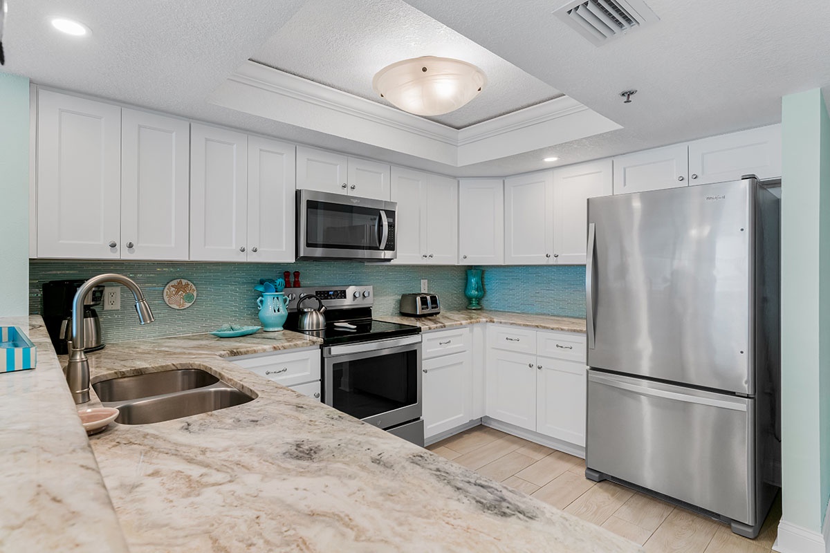 Your fully equipped kitchen features granite countertops, stainless steel appliances, and a soothing turquoise backsplash—perfect for preparing memorable meals.