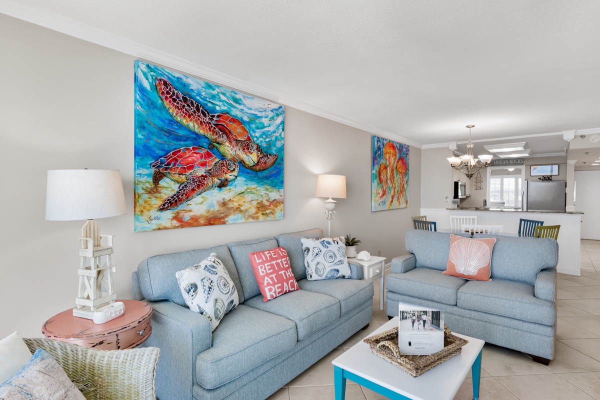 Unwind on plush sofas beneath vibrant sea turtle art in your bright, coastal-themed living space with ocean-inspired decor and pillows.