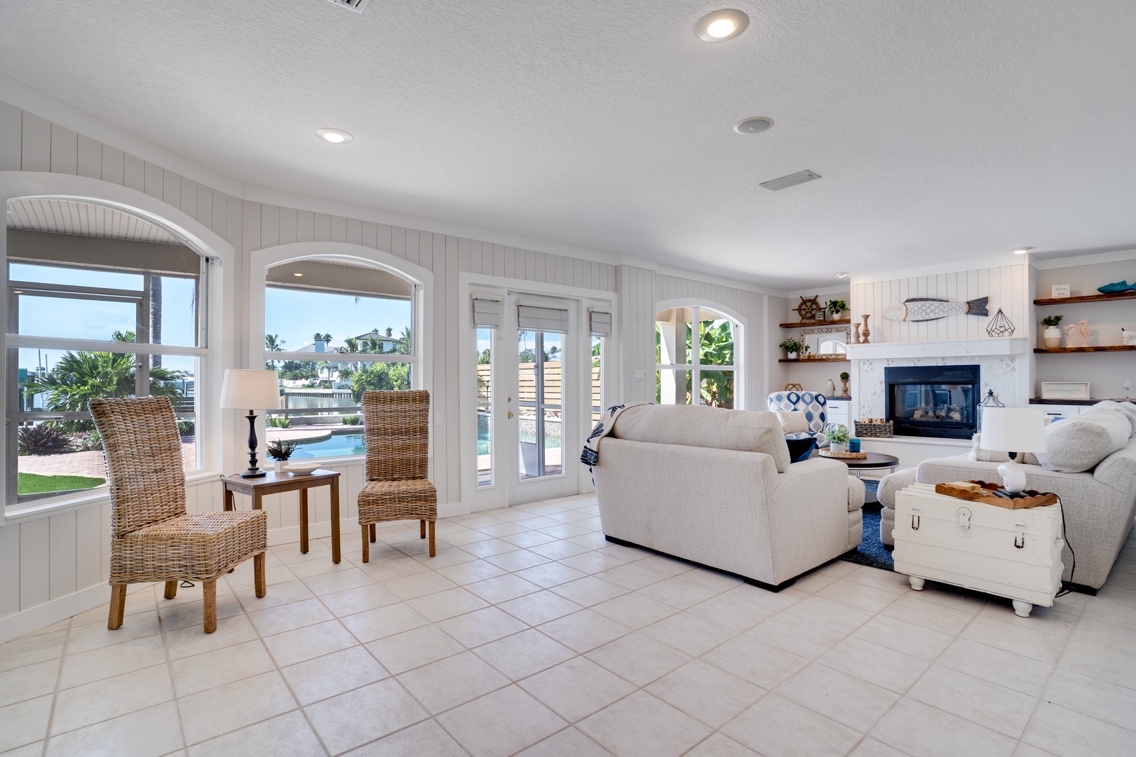 Relax in your coastal living room with nautical touches, where French doors reveal pool views and comfortable seating awaits your arrival.