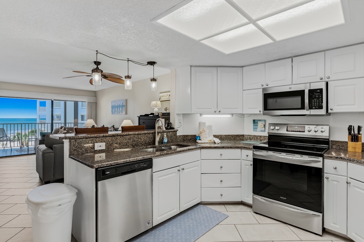 Your fully equipped kitchen with granite counters and stainless appliances opens to a bright living space with stunning ocean views framed by floor-to-ceiling glass.