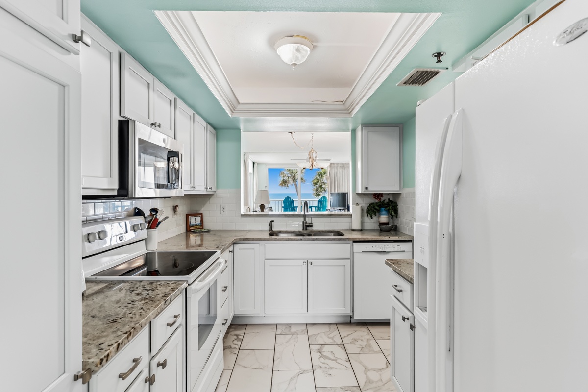 Picture yourself preparing meals in this bright, fully equipped kitchen with modern appliances and stunning ocean views just beyond the pass-through window—your perfect beachside retreat awaits.