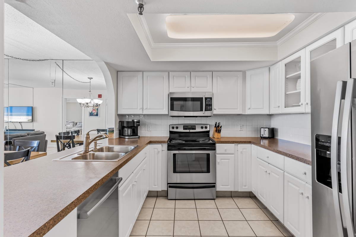 Your spacious kitchen awaits with crisp white cabinets, modern appliances, and warm countertops perfect for preparing memorable vacation meals together.