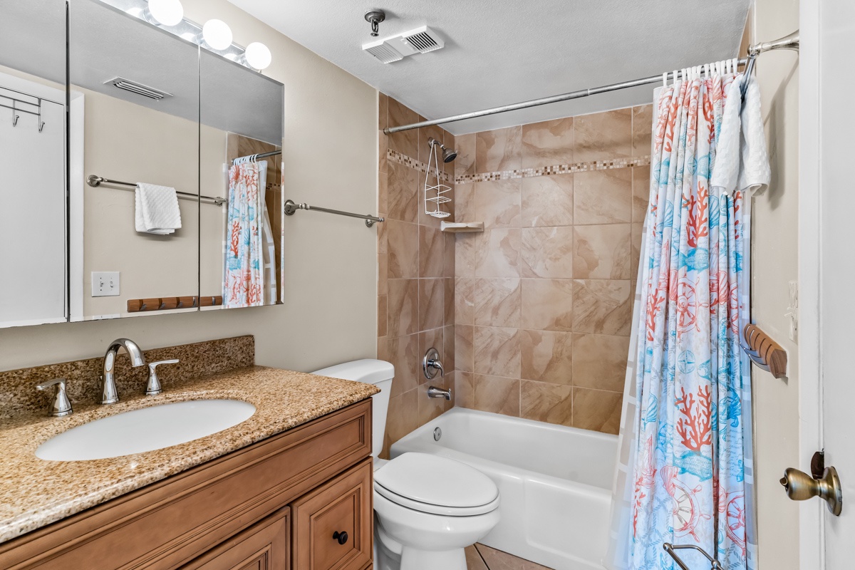 Your bathroom features granite counters, tiled shower with coastal charm curtain—perfect for refreshing after beach days.