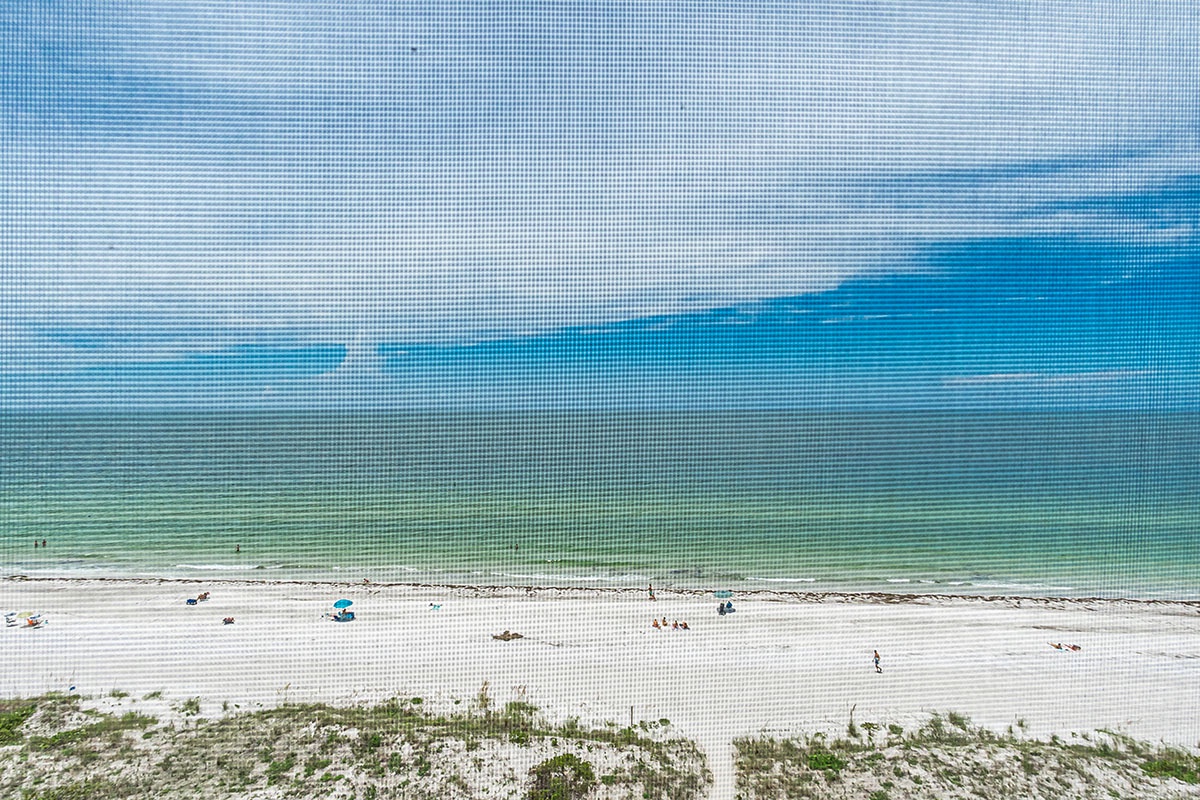 Pristine white sand beach stretches along turquoise Gulf waters, creating a stunning coastal paradise near the property.