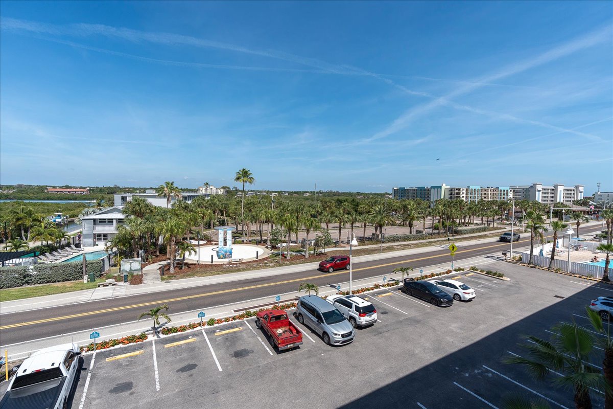 The property is located in a sunny coastal area with palm-lined streets, ample parking, and nearby buildings, offering convenient access to the surrounding neighborhood.