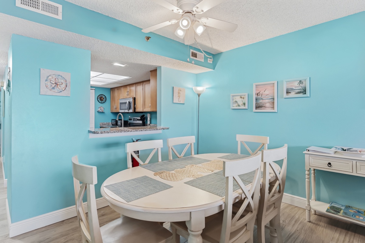 Step into your coastal dining space where turquoise walls and beach-inspired artwork create a breezy, refreshing atmosphere. The white round table awaits your morning coffee or evening meals.