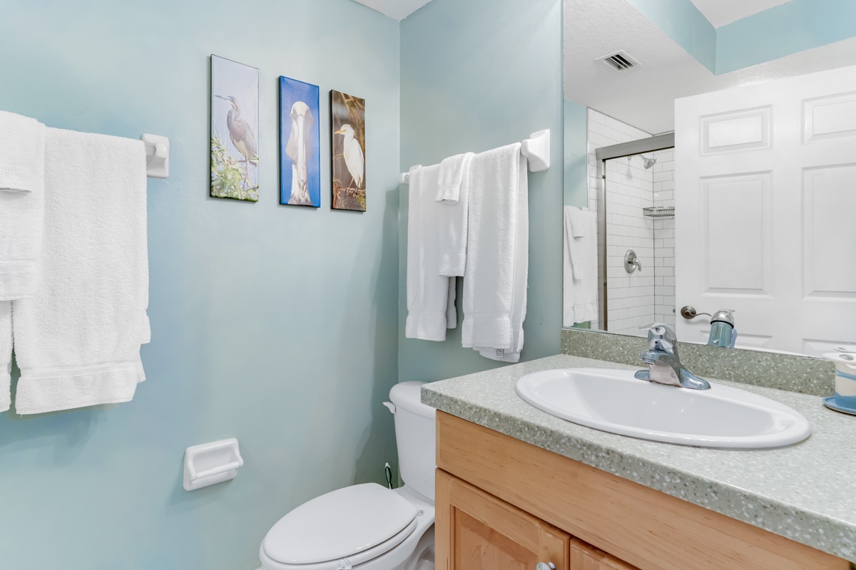 Refresh in your serene spa-like bathroom with soft aqua walls, fluffy towels, and charming coastal artwork creating a peaceful retreat.