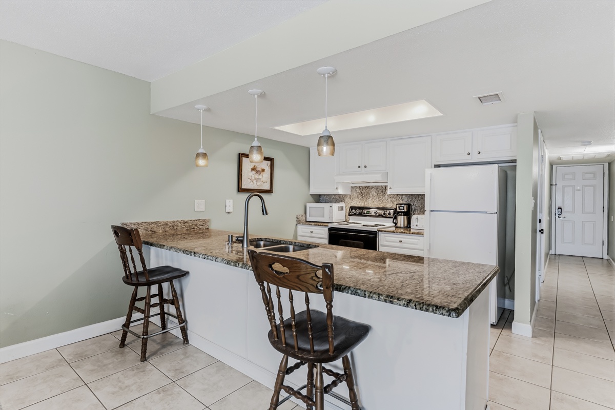 Your fully equipped kitchen awaits, complete with granite countertops, bar seating, and everything you need to prepare meals during your stay.