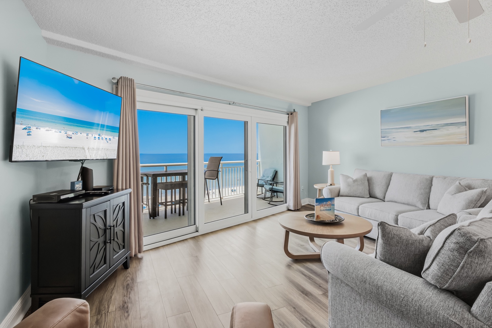 Settle into your bright living room where soft blue walls meet sweeping ocean views through sliding glass doors. Sink into plush seating, step onto your private balcony, and let the sea breeze and endless horizon become your favorite backdrop.
