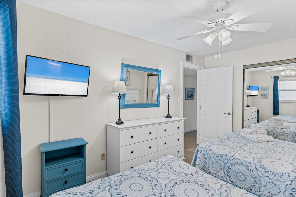Unwind in your bright bedroom with 2 Queen beds, wall-mounted TV, and coastal blue accents that create a peaceful retreat.