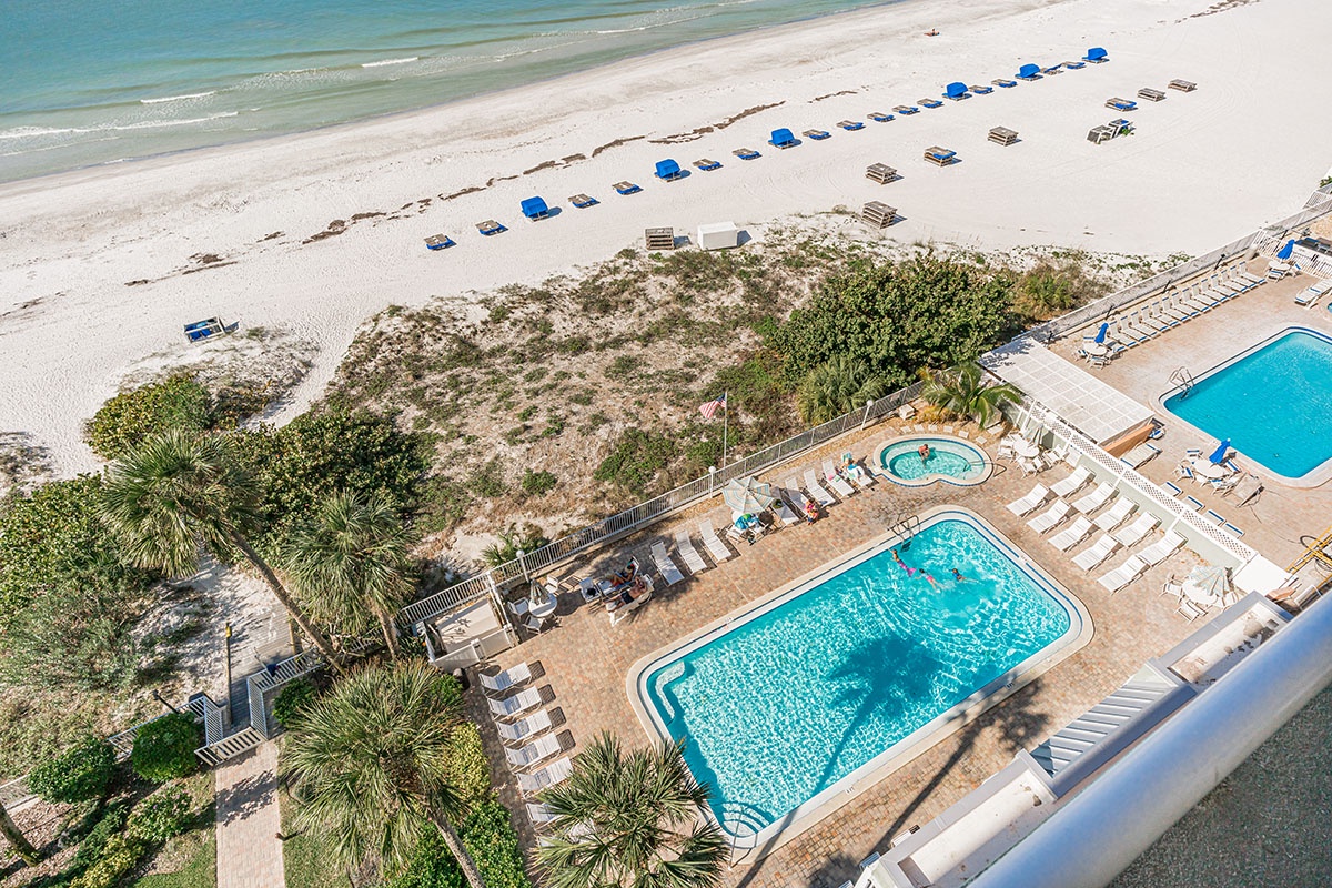 Beachfront property featuring sparkling pools, pristine white sand, and crystal-clear turquoise waters stretching endlessly along the coastline.