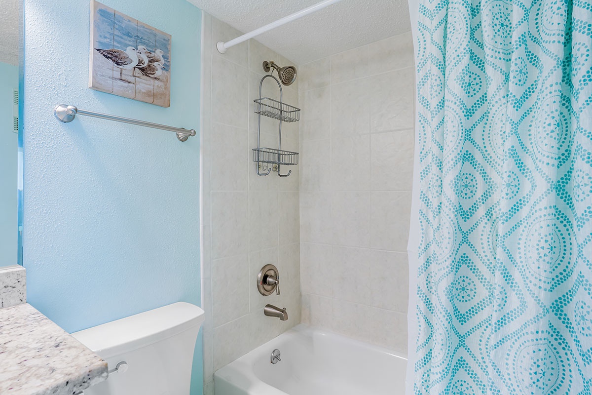 Unwind in your fresh, coastal-inspired bathroom featuring soothing blue tones and a rejuvenating shower-tub combo.
