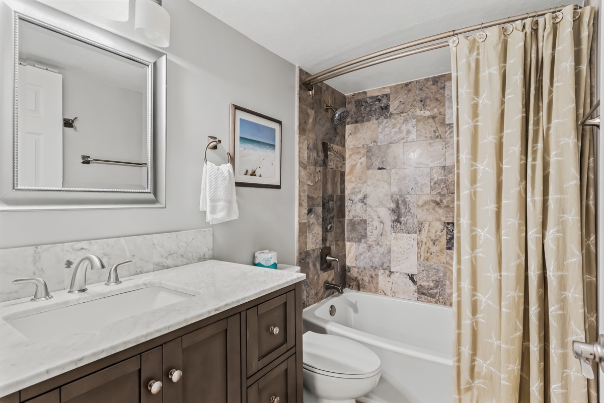 Step into your beautifully appointed bathroom, where marble-style tiles and soft gray tones create a serene retreat. The spacious vanity and elegant tub-shower combo invite you to unwind after a day of exploration.