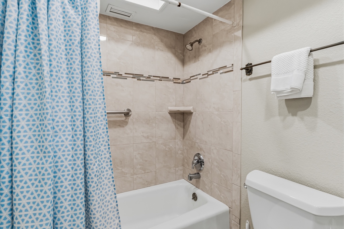 Freshen up in your private bathroom featuring a tub-shower combo, soft towels, and thoughtful details like a skylight for natural light.