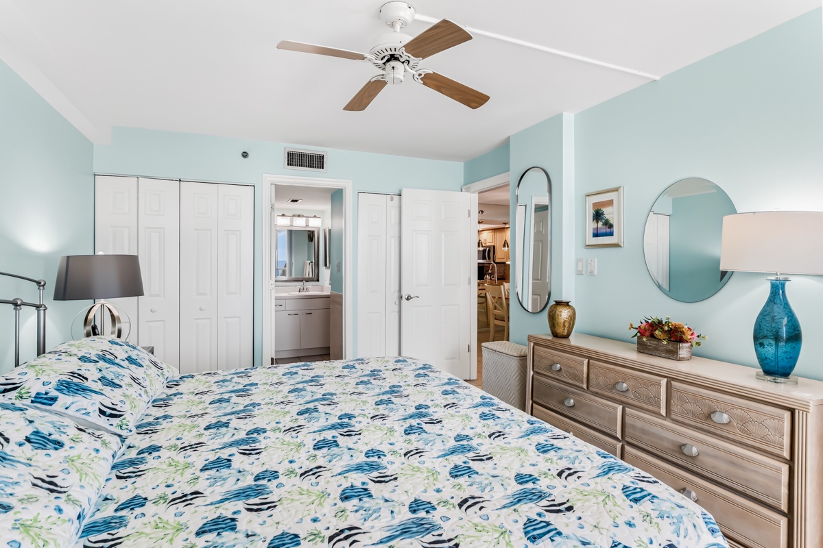 Retreat to your peaceful King bedroom with soothing coastal colors, a ceiling fan, and an en-suite bathroom just steps away for your convenience and comfort.