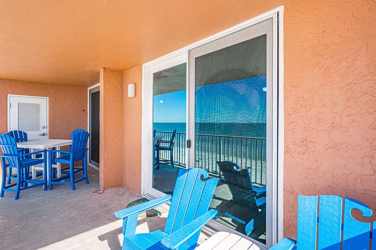 Your private oceanfront balcony awaits with vibrant blue chairs where you can sip morning coffee while watching waves dance beyond the glass.